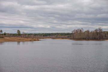 Spring landscape, forest, river, lake, cloudy day, storm clouds.
