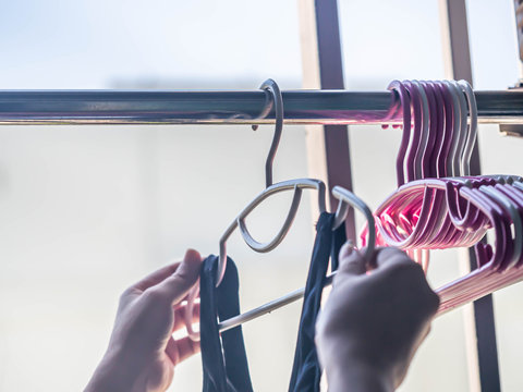 Woman 's hand and stack of clothes hanger with black sports bras after laundry or washing process.