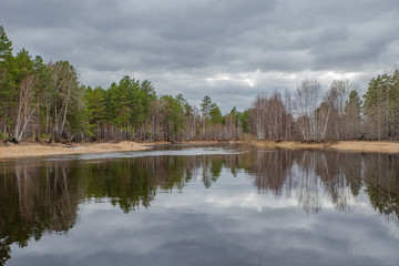 Spring landscape, forest, river, lake, cloudy day, storm clouds. Open space.