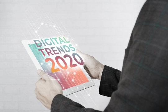 Man Hand Holding White Tablet With Digital Trends 2020 On Screen. New Trends Digital Marketing, Business And Technology Concept.