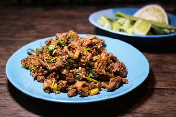 Spicy duck minced salad with fresh vegetabes on wood table. Thai local food recipe Larb Ped yummy food menu.