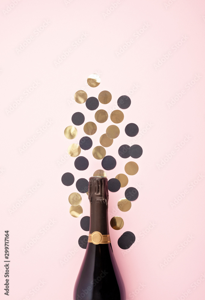 Poster Creative photo of champagne bottle with confetti on pink background. Flat lay of christmas, anniversary, new year celebration