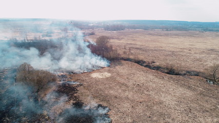 Fototapeta na wymiar Forest and field fire. Dry grass burns, natural disaster. Aerial view. Smooth flight over the burning place.