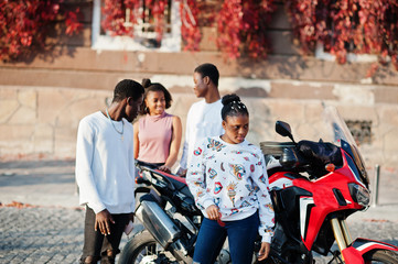 Four african friends walking the streets against motorbike.