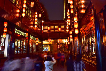 Fototapeta na wymiar Young Woman Takes a Photo of Chinese Lanterns Hanging from Old Traditional Buildings Along Chengdu's Famous Jinli Street at Night - Chengdu, China (Summer) 