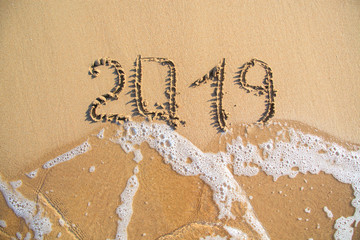 2019 text painted on the sand. Water washed away the text.