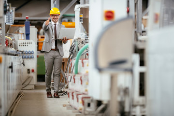 Businessman in warehouse. Young architect with helmet in suit.