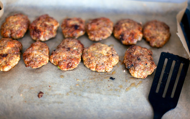 Homemade cutlets on baking sheet with spatula.