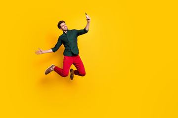 Full length photo of positive cheerful guy on spring journey vacation jump take selfie blogging...