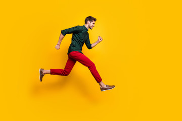 Fototapeta na wymiar Full size profile side photo of positive cheerful guy jump run fast want hurry to sales discounts wear casual style clothes sneakers isolated over yellow color background
