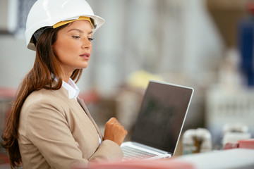 Businesswoman in warehouse. Young female architect with helmet in suit. Close up.