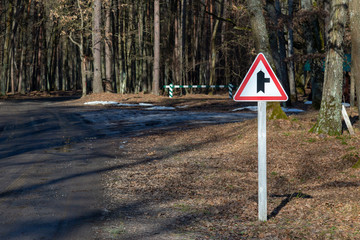 Side road right sign on a stand in the road through the forest.