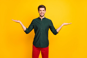 Photo of cheerful positive handsome guy smiling toothily holding two objects of one item showing you both sides isolated vivid color background