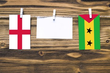 Hanging flags of England and Sao Tome And Principe attached to rope with clothes pins with copy...