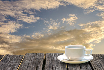 Coffee cup on wooden table with morning sky background
