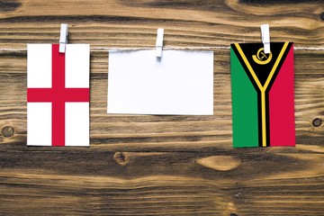Hanging flags of England and Vanuatu attached to rope with clothes pins with copy space on white...