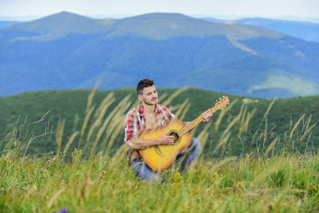 Fototapeta na wymiar Classic Cool. acoustic guitar player. country music song. sexy man with guitar in checkered shirt. hipster fashion. western camping and hiking. happy and free. cowboy man play guitar outdoor