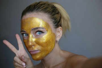 Portrait of young woman posing with golden face mask. Skin acne treatment. Golden face mask. 