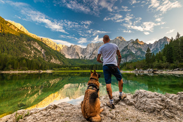 Adventure Man Standing With Dog at Beautiful Lake, Fusine Lake , Italy