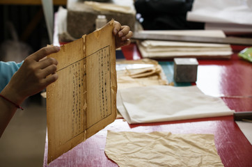 Traditional Chinese book and calligraphy restorer laboratory. Master hands at work close-up.