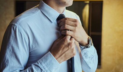 man in shirt dressing up and adjusting tie on neck at home. Men Fashion