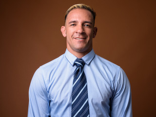 Studio shot of businessman smiling against brown background