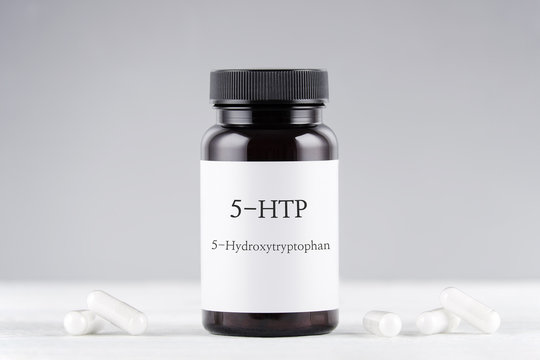 nutritional supplement 5-HTP hydroxytryptophan, bottle and capsules on gray
