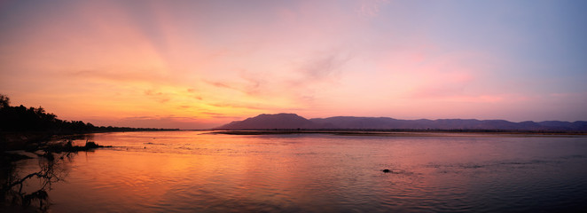 Panoramic view of sunset on the african Zambezi river. The dramatic, red sky reflects on the surface of the border river. View over the flood plain to the mountains on the Zambian side of the river. © Martin Mecnarowski