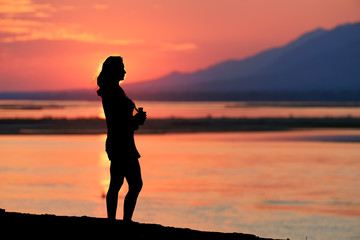 Silhoutte of woman traveller against sunset, mirroring on Zambezi river. Adventure walking safari...