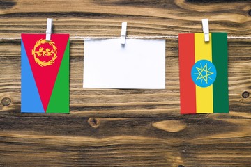 Hanging flags of Eritrea and Ethiopia attached to rope with clothes pins with copy space on white...