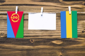 Hanging flags of Eritrea and Gabon attached to rope with clothes pins with copy space on white note...