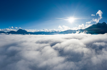 Fototapeta na wymiar aerial view over cloud bank to tirol mountain alps with sun beams