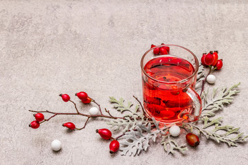 Hot dog-rose tea. Winter drink for good mood with fresh berries, leaves and candies. Stone concrete...
