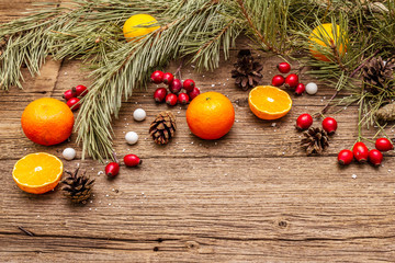 Spirit Christmas background. Fresh mandarins, dog-rose berries, candies, pine branches and cones, artificial snow