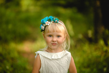 Little girl in a white dress with headband flower