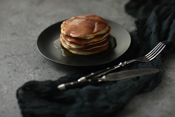 pancakes on a black plate with syrup