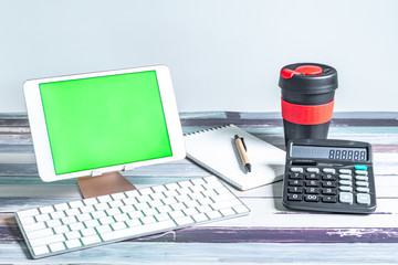 Stationery, reusable cup, keyboard and mobile tablet with green screen