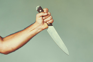 Hand of caucasian man holding a knife isolated on a gray background. Man hold knife - aggression....