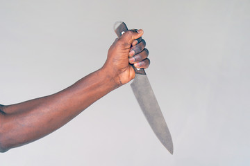 Hand of african man holding a knife isolated on a gray background. African man hold knife -...
