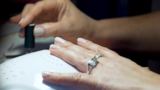 Woman doing manicure at home. Girl do nails herself. Old hands close up