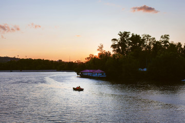 A man in a boat floats on the river at sunset. The athlete in the boat is not far from the...