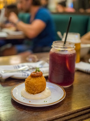 Spanish tapa called bomba served at a restaurant in Barcelona, Spain. The famous appetizer is on a white plate on a wooden table