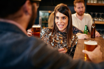 Group of friends drinking beer, chatting and having good time at pub. Night out.