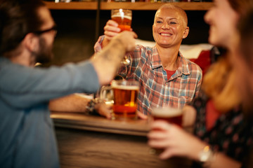 Cheerful caucasian waitress giving pint of beer to man. Pub interior.