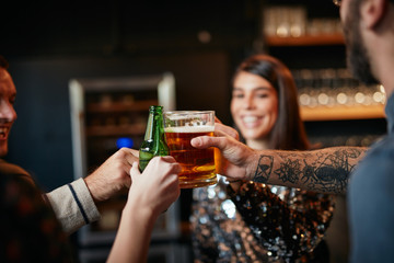 Friends standing in bar and toasting with beer.