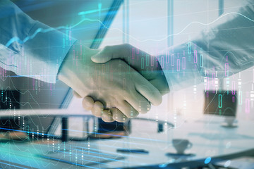 Multi exposure of financial graph on office background with two businessmen handshake. Concept of success in business