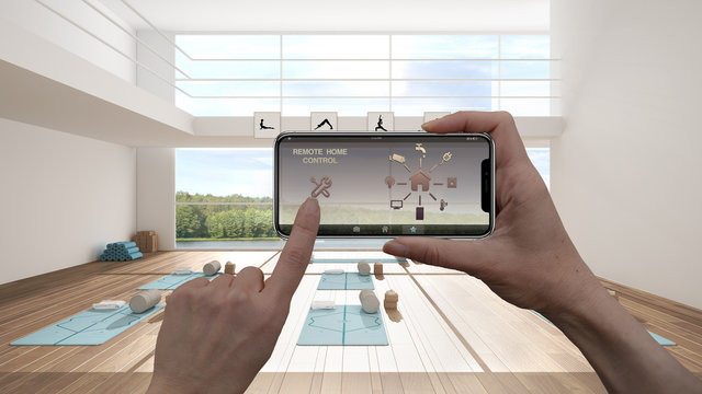 Remote home control system on a digital smart phone tablet. Device with app icons. Interior of yoga studio with mats, pillows and accessories in the background, architecture design