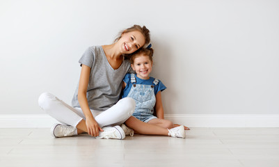 happy family mother (big sister) and child daughter near an empty wall.