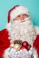 Santa Claus holding a handful of Christmas tree decorations