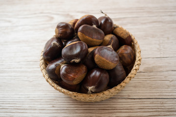top view of chestnuts in a wicker basket on a wooden table